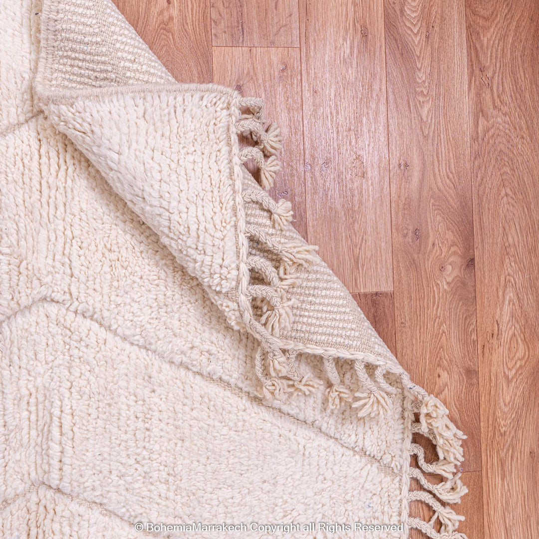 White Moroccan rug with subtle zigzag design, featuring hand-knotted wool and fringes, ideal for modern or boho homes.