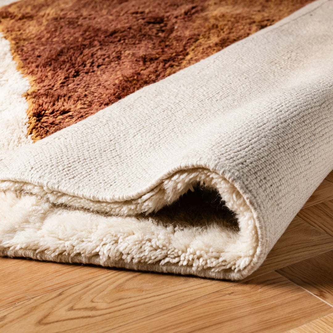Close-up of a Custom Beni Mrirt Moroccan Rug in brown and cream, showcasing plush wool texture on a wooden floor.