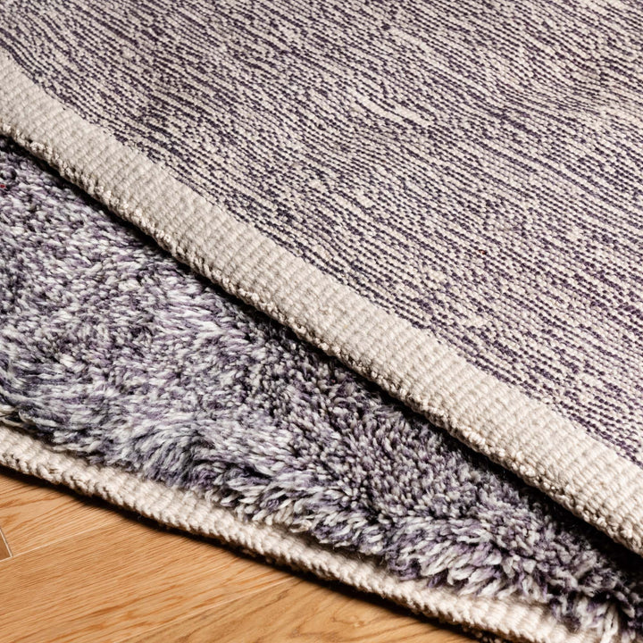 Close up of a handmade Moroccan wool rug with plush texture and abstract geometric pattern in grey tones, showcasing intricate craftsmanship.