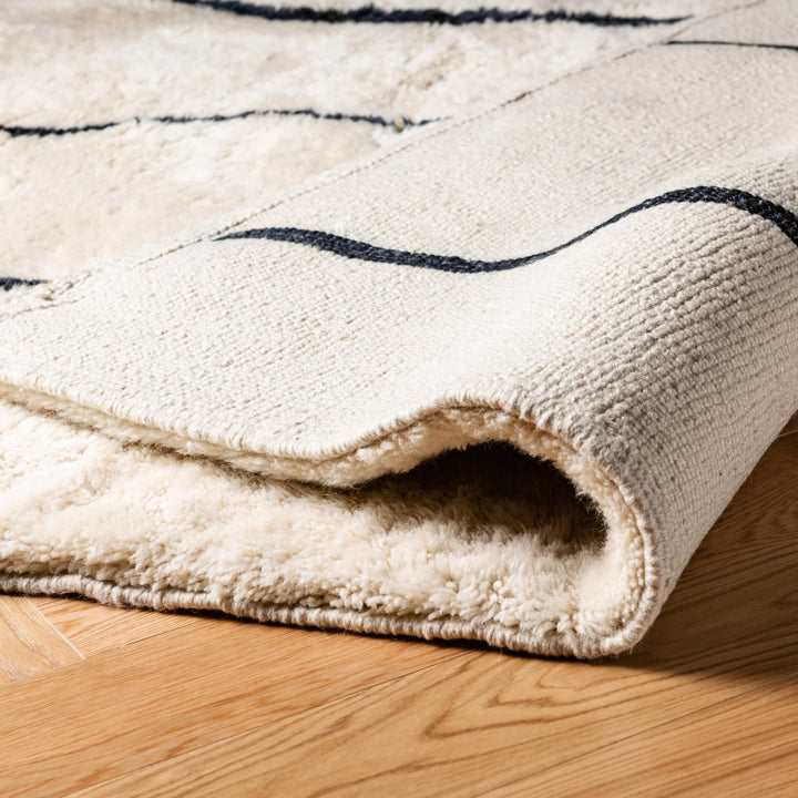 Close-up of plush handmade custom Beni Mrirt Moroccan wool rug with abstract Berber motifs on a hardwood floor.