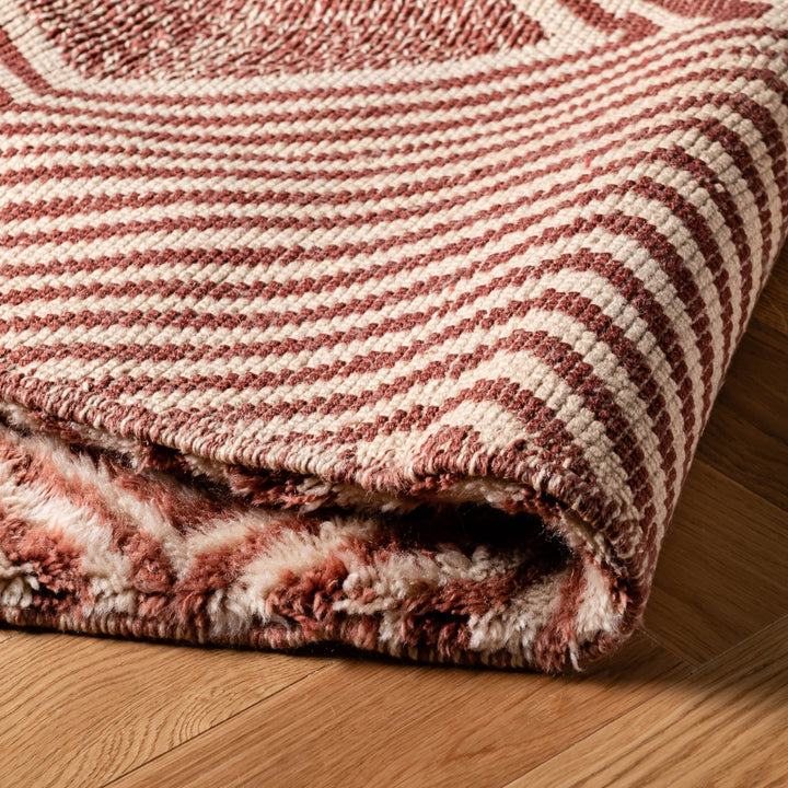 Close-up of a handmade Moroccan Beni Mrirt wool rug in rose and clay tones, featuring intricate geometric patterns.