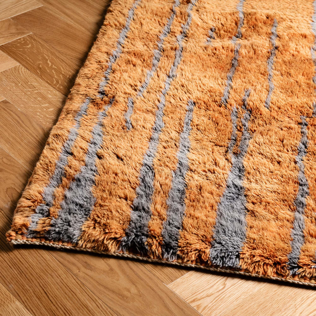 Beni Mrirt Moroccan wool rug with vertical lines on wood floor, warm tones, handwoven craftsmanship, traditional Moroccan style.