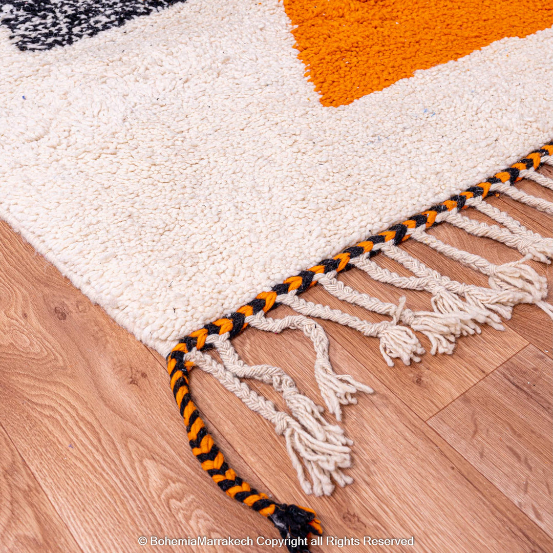 Abstract Beni Ourain Moroccan rug with colorful geometric shapes in orange, pink, black, and teal on a white wool background