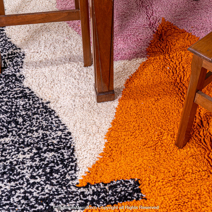 Abstract Beni Ourain Moroccan rug with colorful geometric shapes in orange, pink, black, and teal on a white wool background