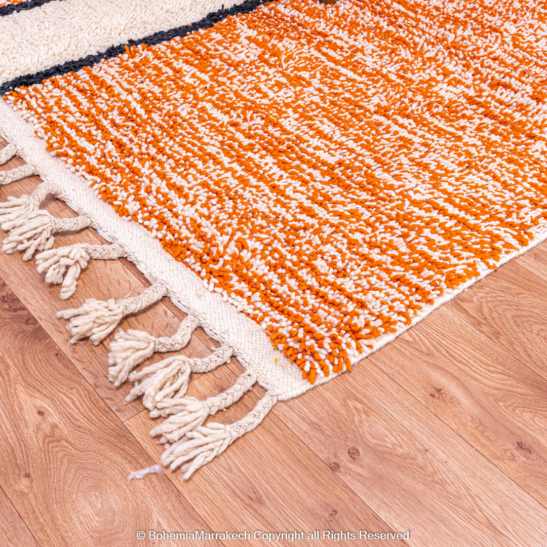 Colorful Moroccan rug with orange base and geometric wool patterns in black, cream, turquoise, and pink