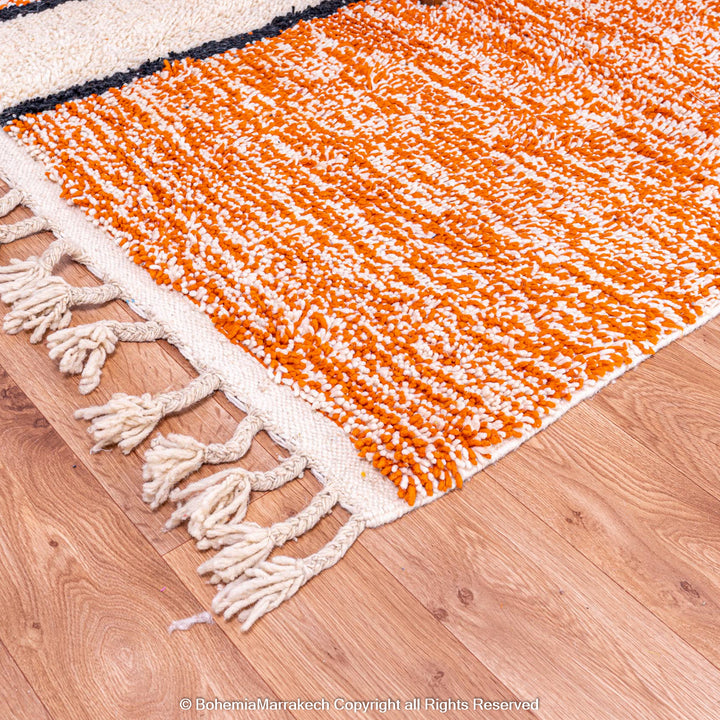 Colorful Moroccan rug with orange base and geometric wool patterns in black, cream, turquoise, and pink