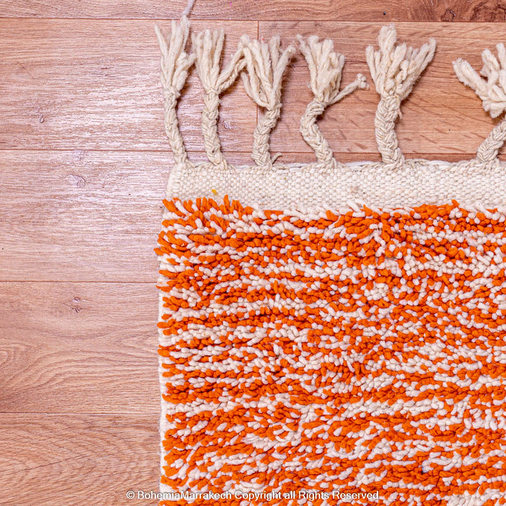 Colorful Moroccan rug with orange base and geometric wool patterns in black, cream, turquoise, and pink