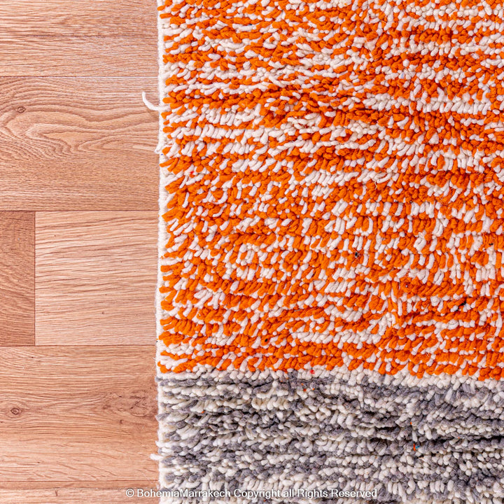 Colorful Moroccan rug with orange base and geometric wool patterns in black, cream, turquoise, and pink