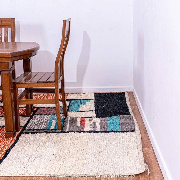 Colorful Moroccan rug with orange base and geometric wool patterns in black, cream, turquoise, and pink
