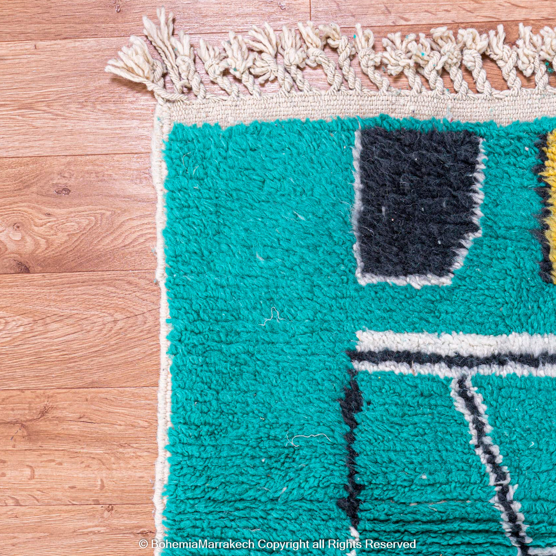 Handmade green Moroccan rug with bright diamond line patterns on deep green background