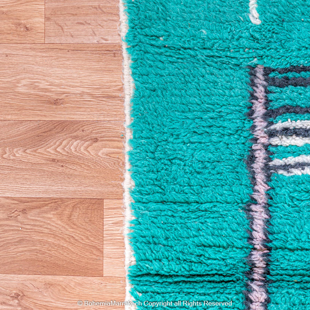 Handmade green Moroccan rug with bright diamond line patterns on deep green background