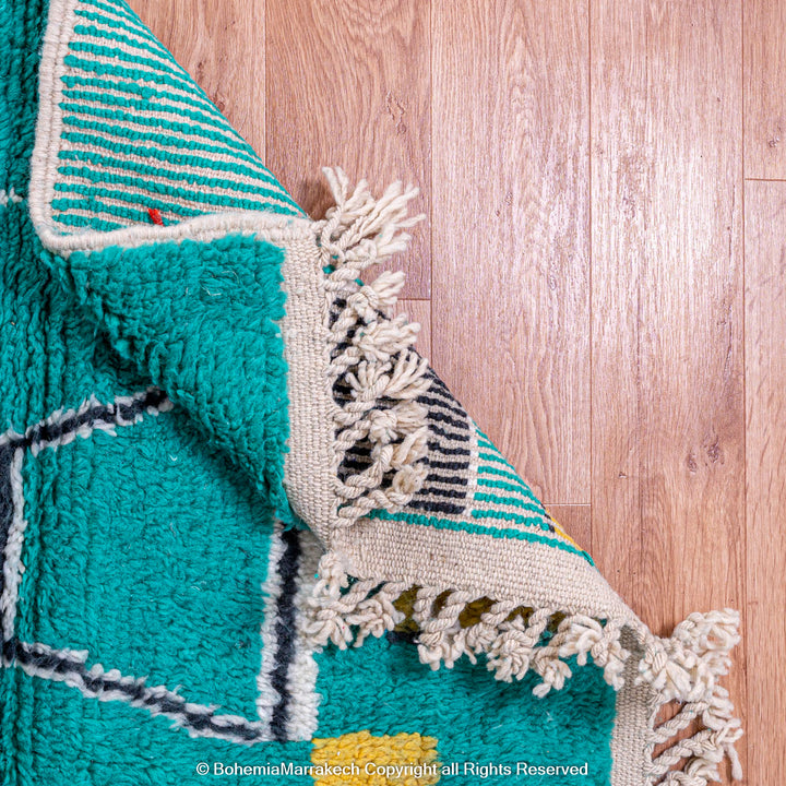 Handmade green Moroccan rug with bright diamond line patterns on deep green background