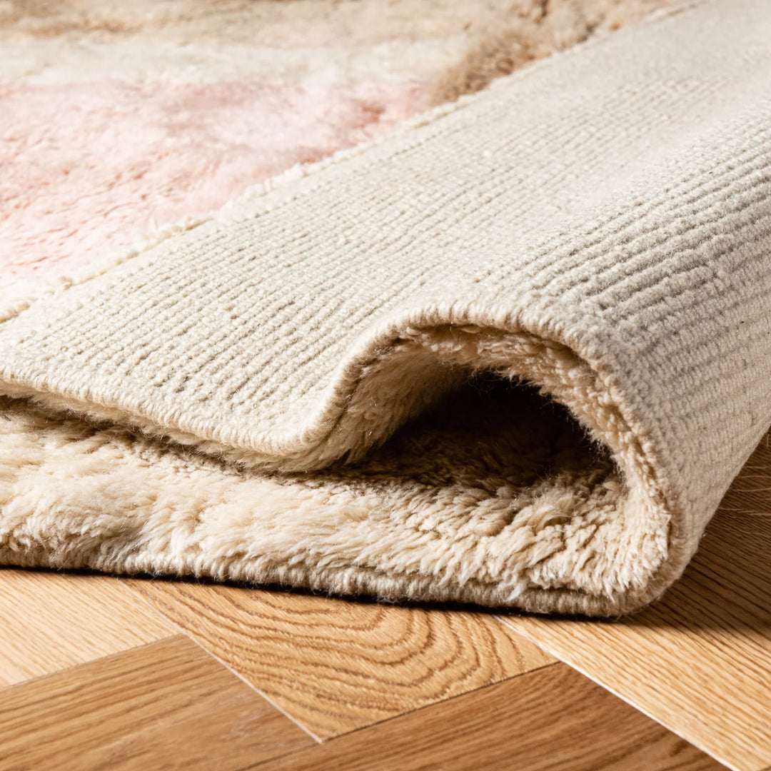 Close-up of a handmade Moroccan rug showcasing plush texture and geometric pattern on a wooden floor.