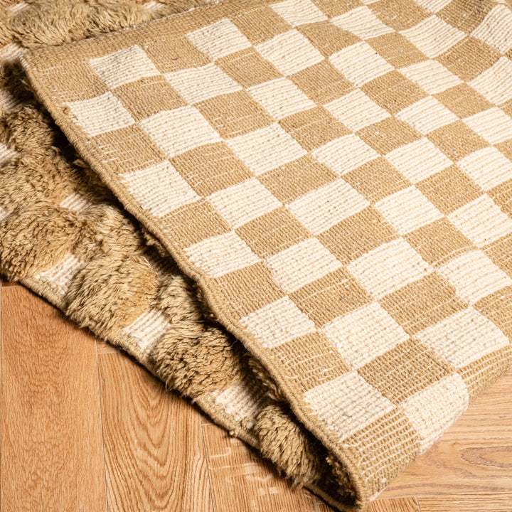 Handmade Moroccan rug with beige and cream checkerboard pattern on wooden floor