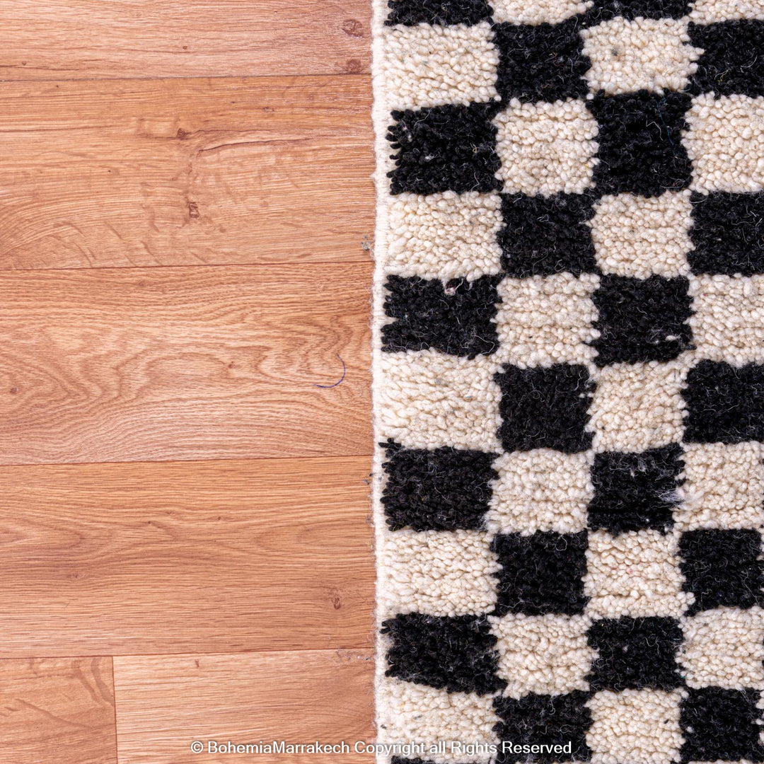 Black and white checkered Moroccan Berber rug on a wooden floor.
