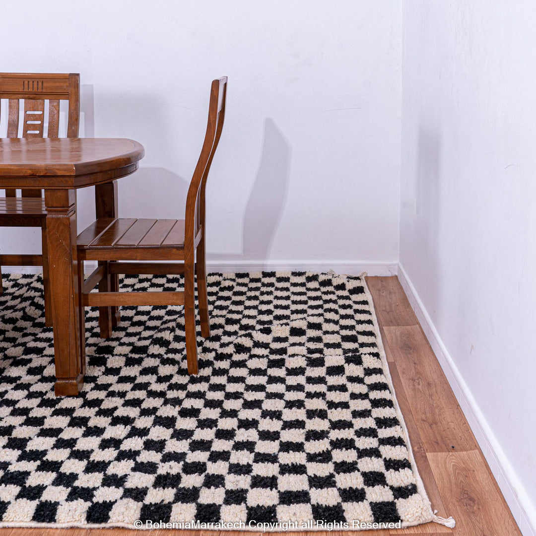 Black and White Checkered Moroccan Rug under dining table, handcrafted wool, adds modern contrast, Moroccan Berber craftsmanship.