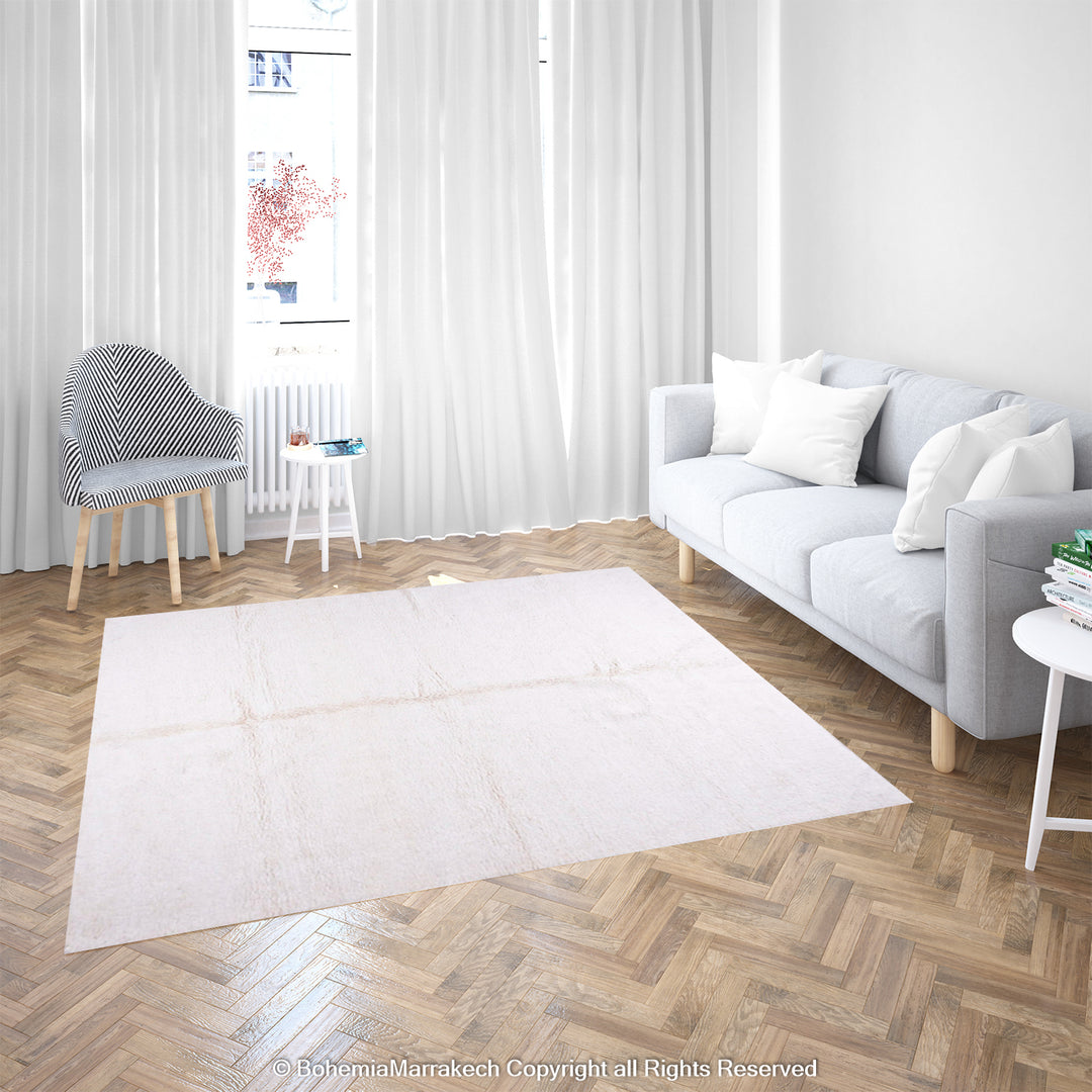 Large plain white Moroccan Berber wool rug in a minimalist living room with natural light and modern decor.