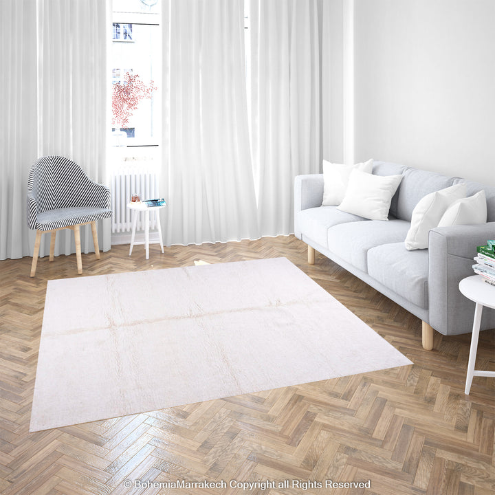 Large plain white Moroccan Berber wool rug in a minimalist living room with natural light and modern decor.