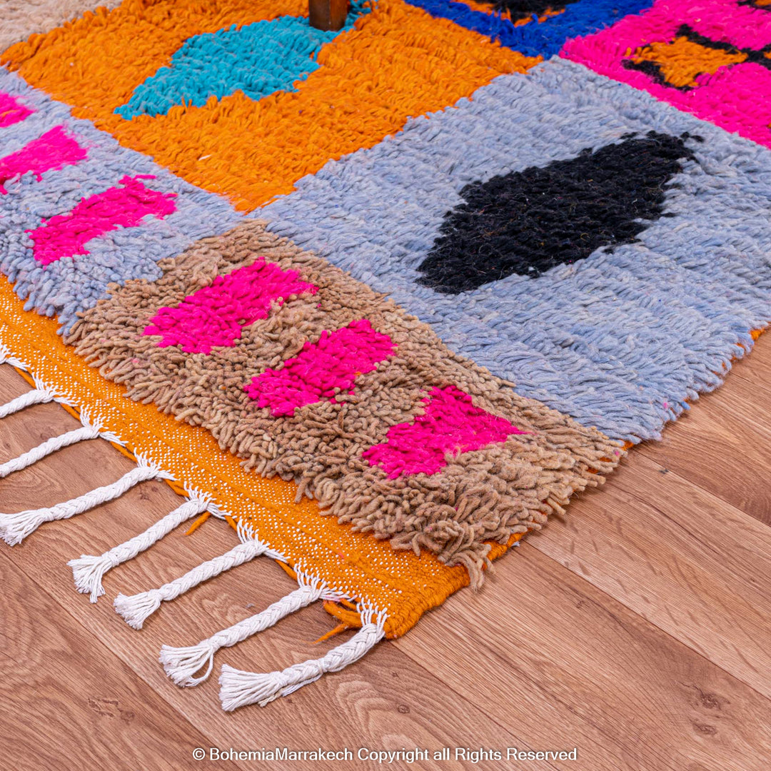 Colorful Moroccan wool rug with geometric design, featuring pink, blue, orange, and black motifs. Handwoven Berber art. 8x10 size.