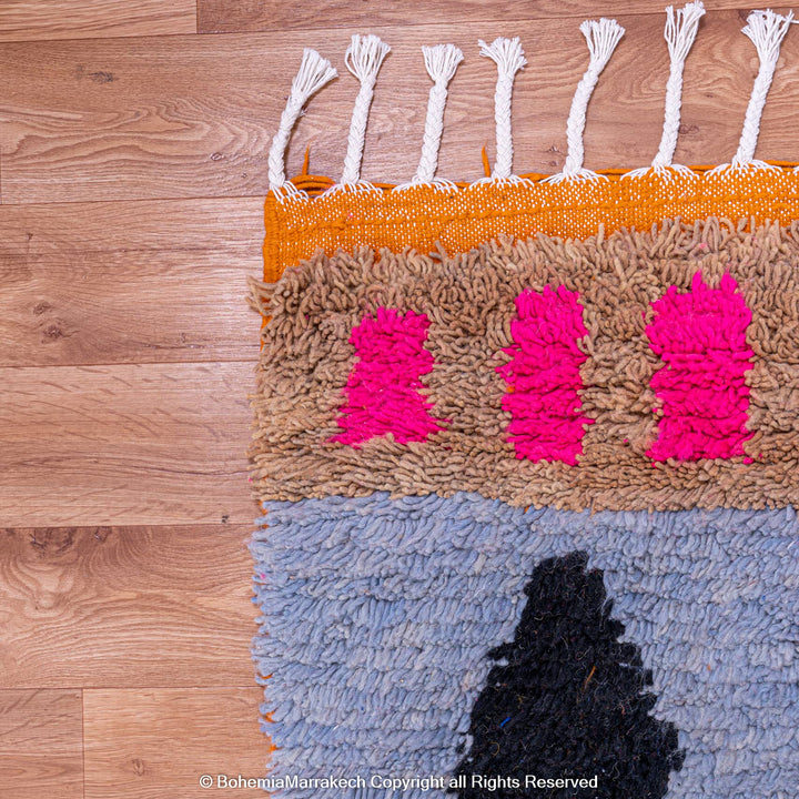 Colorful Moroccan wool rug with geometric shapes, featuring pink, blue, and black motifs. Handmade by Berber women. Moroccan carpet.