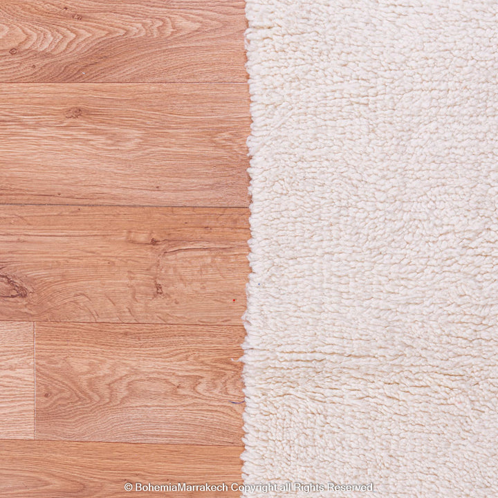 Plain White Moroccan Wool Beni Ourain Rug against wooden floor, traditional Berber style, large area rug from Morocco.
