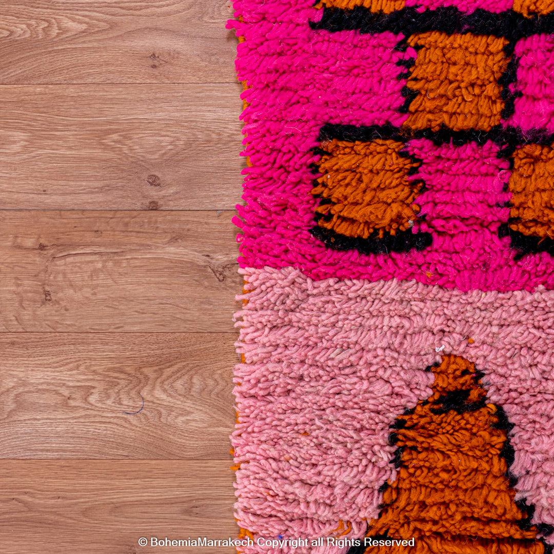 Colorful Moroccan Patchwork Rug featuring pink and orange geometric patterns, handwoven from natural wool by Berber artisans.
