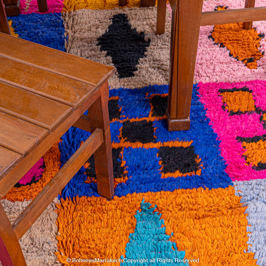 Colorful Moroccan wool rug with geometric patterns, featuring vibrant pink, blue, and orange, handcrafted by Berber women. 8x10.