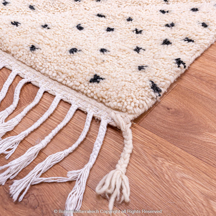 White Moroccan Beni Ourain rug with black dots, handcrafted wool, traditional Moroccan carpet with tassels on wooden floor