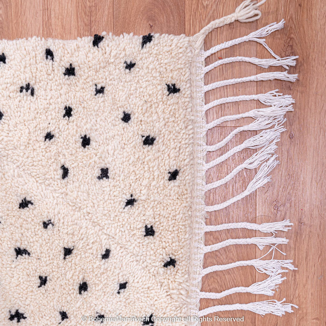 White Moroccan Beni Ourain rug with black dots, handcrafted from 100% natural wool by Berber artisans; perfect for modern interiors.