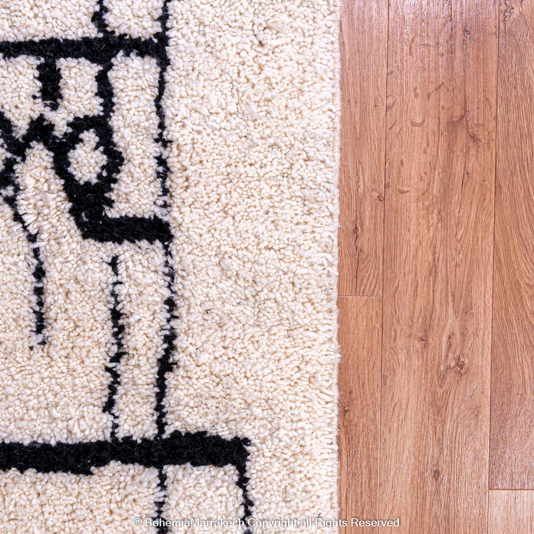 Handmade Abstract Face Moroccan Rug in wool, featuring black face design, wood floor background, modern Berber art, Morocco inspired.
