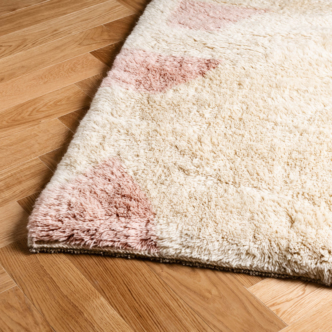 Custom Moroccan wool rug with soft pink geometric design on a hardwood floor.