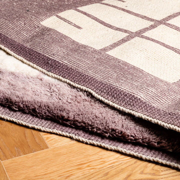 Custom Moroccan wool rug with lilac border and grid pattern on wood floor, showcasing plush texture and modern Berber design.