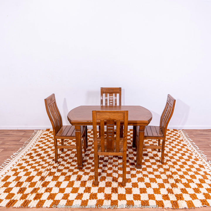 Yellow white checkered Moroccan wool rug under wooden dining set; handcrafted in Atlas Mountains; vibrant traditional design.