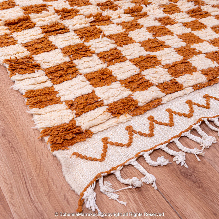 Yellow white checkered Moroccan wool rug, handmade with Berber motifs, on wooden floor, traditional artisan design.