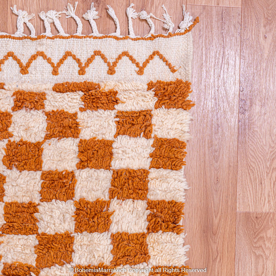 Yellow and white checkered Moroccan wool rug, handmade with traditional Berber motifs, on wooden floor.