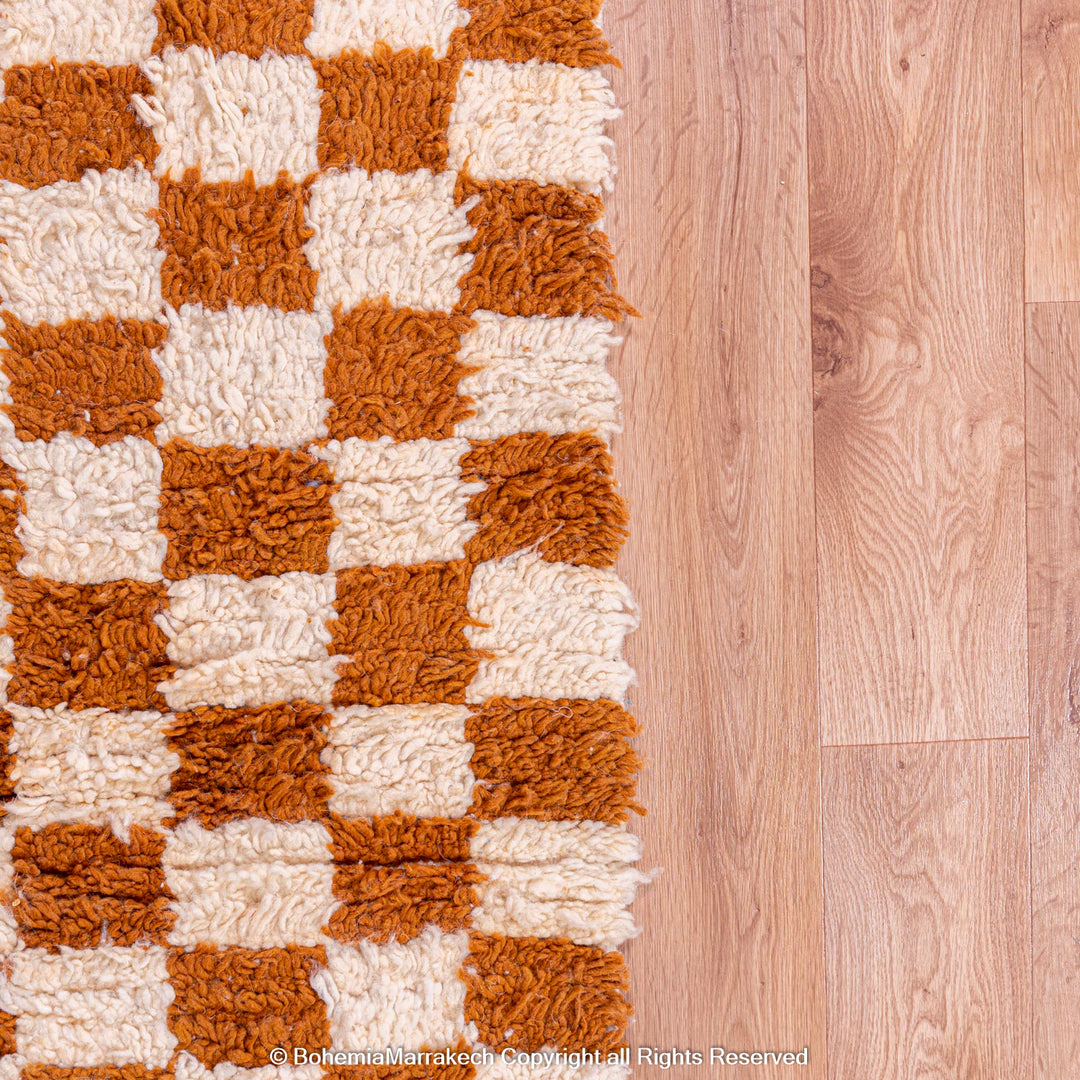 Yellow white checkered Moroccan wool rug on wooden floor, traditional Berber design, handmade area rug.