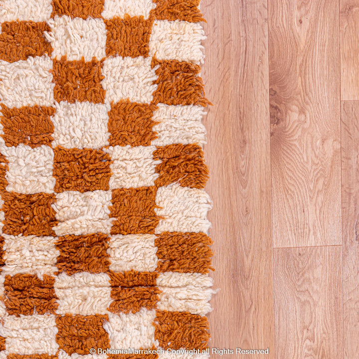 Yellow white checkered Moroccan wool rug on wooden floor, traditional Berber design, handmade area rug.