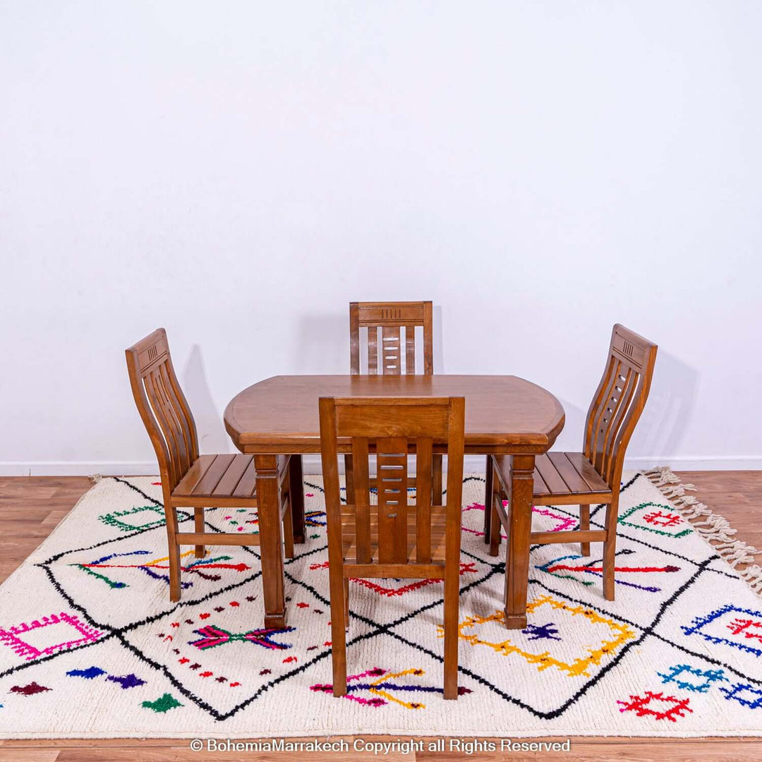 Dining set on Azilal Moroccan rug with vibrant Berber motifs in red, blue, pink; traditional Moroccan decor; wool rug with symbols.