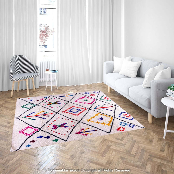 Handmade pink Moroccan Berber rug with colorful tribal symbols on a cream wool background in a modern living room.