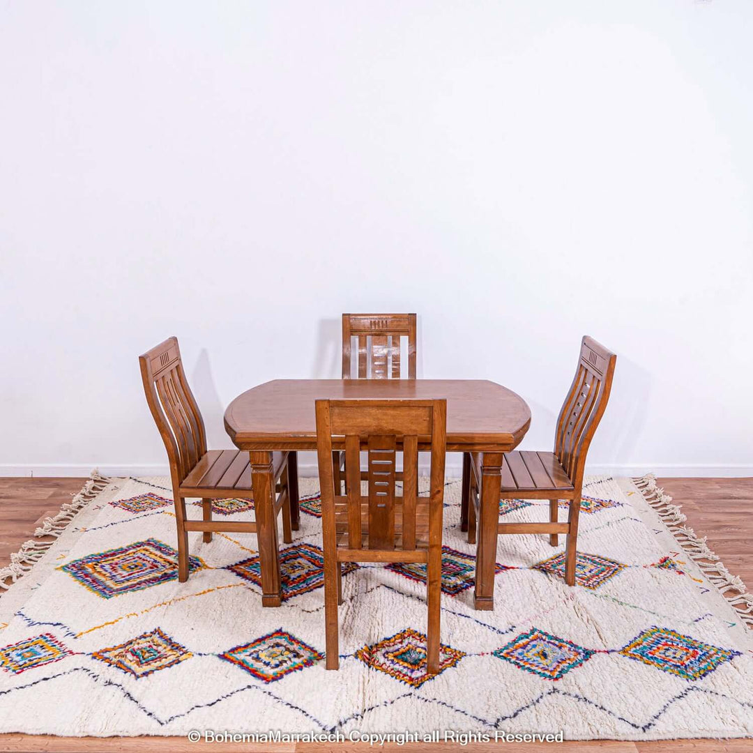 Dining set on colorful Azilal Moroccan rug with diamond Berber motifs, showcasing vibrant traditional artistry.