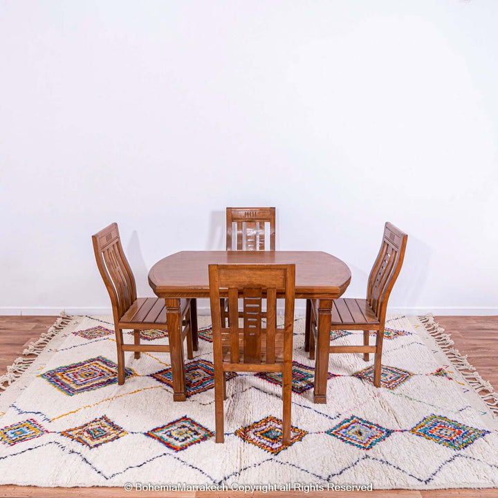Dining set on colorful Azilal Moroccan rug with diamond Berber motifs, showcasing vibrant traditional artistry.