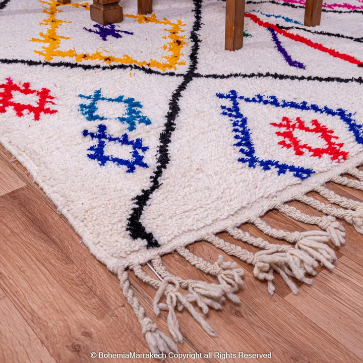 Handmade Azilal Moroccan rug with colorful Berber symbols, cream wool background, traditional tribal art carpet.