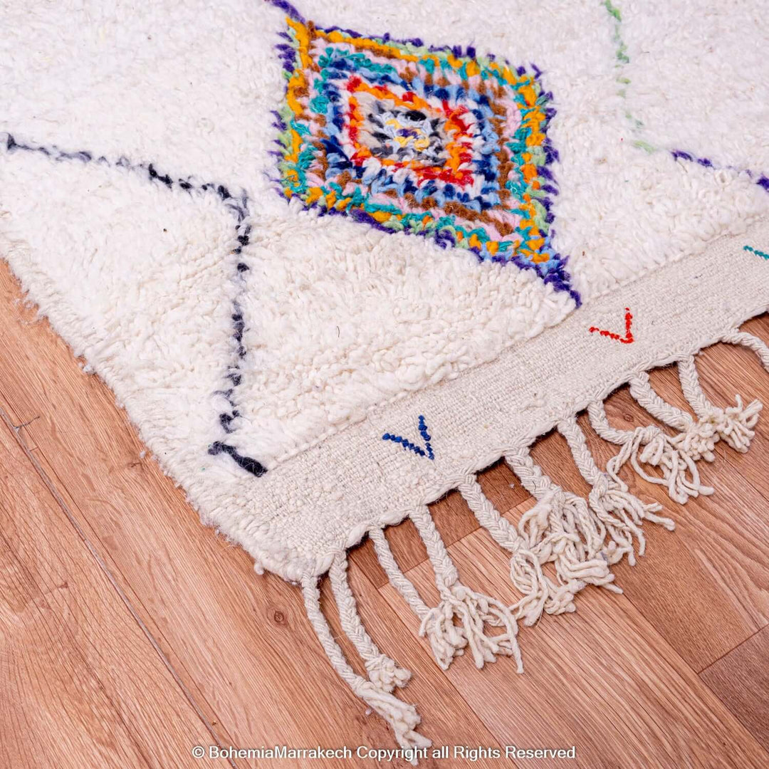 Colorful Azilal Moroccan rug with diamond Berber motifs, handcrafted, traditional Moroccan carpet on wooden floor.