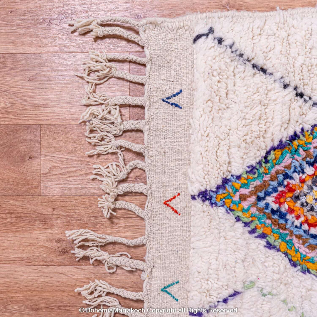 Colorful Azilal Moroccan rug corner with diamond berber motifs and fringe, handmade with vibrant wool by Berber women.