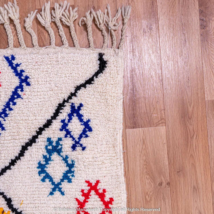 Handmade pink Moroccan Berber rug with colorful tribal symbols on cream wool background, showcasing vibrant ethnic designs.