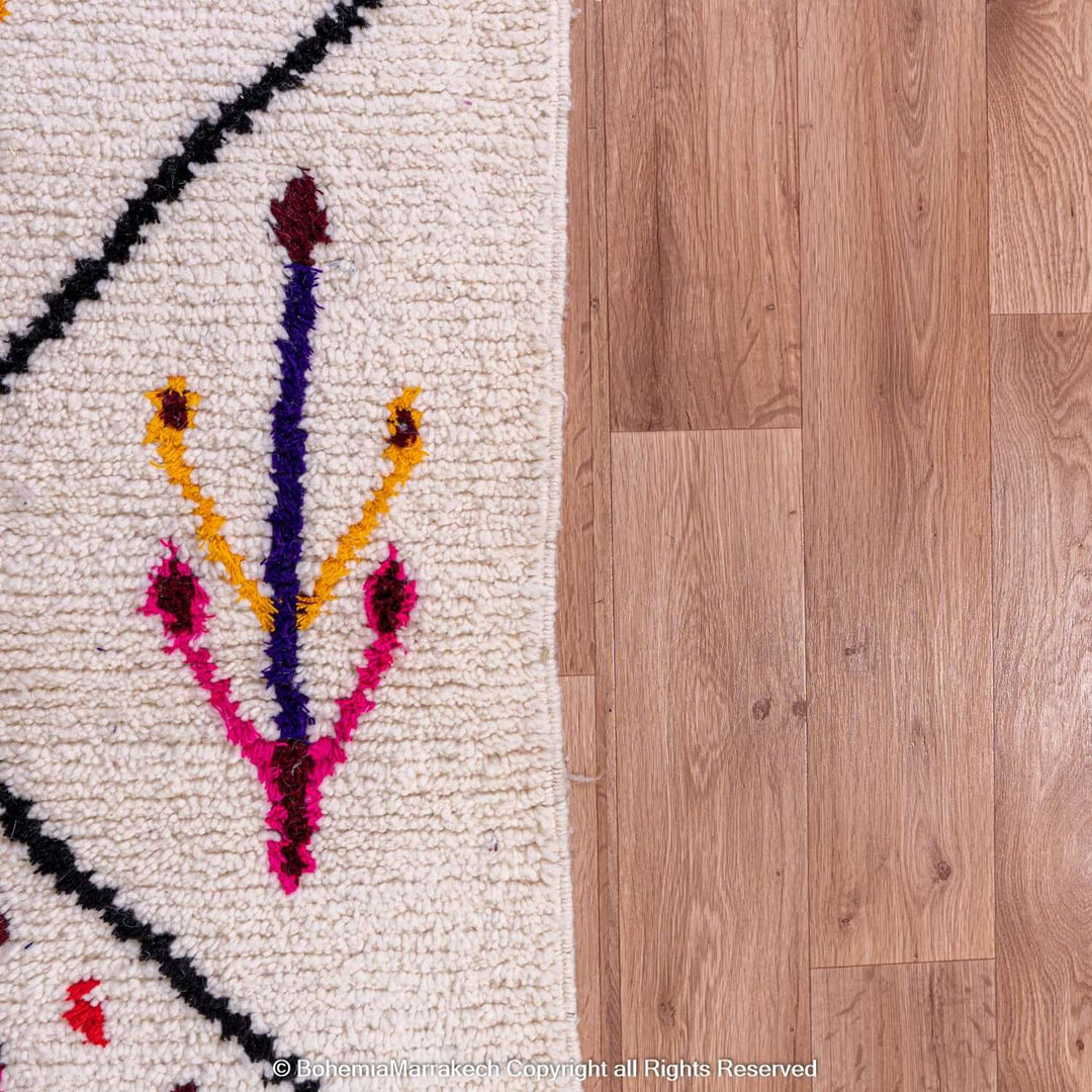 Handmade Azilal Moroccan rug with pink and multicolor Berber symbols on cream wool, showcasing traditional tribal art design.