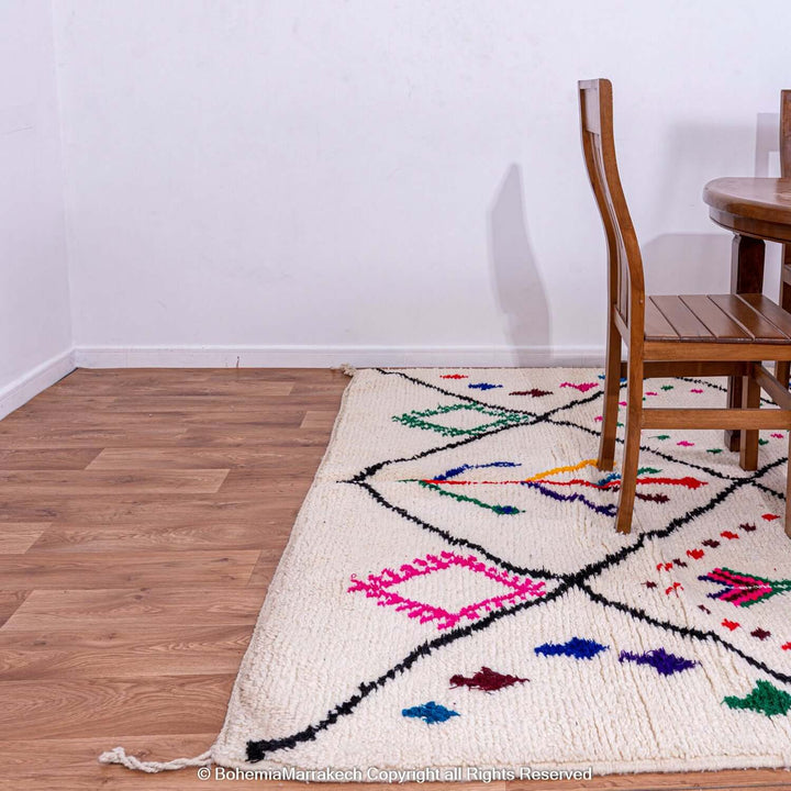 Handmade pink Moroccan Berber rug with colorful symbols on cream wool, perfect for adding cultural depth to any room's decor.
