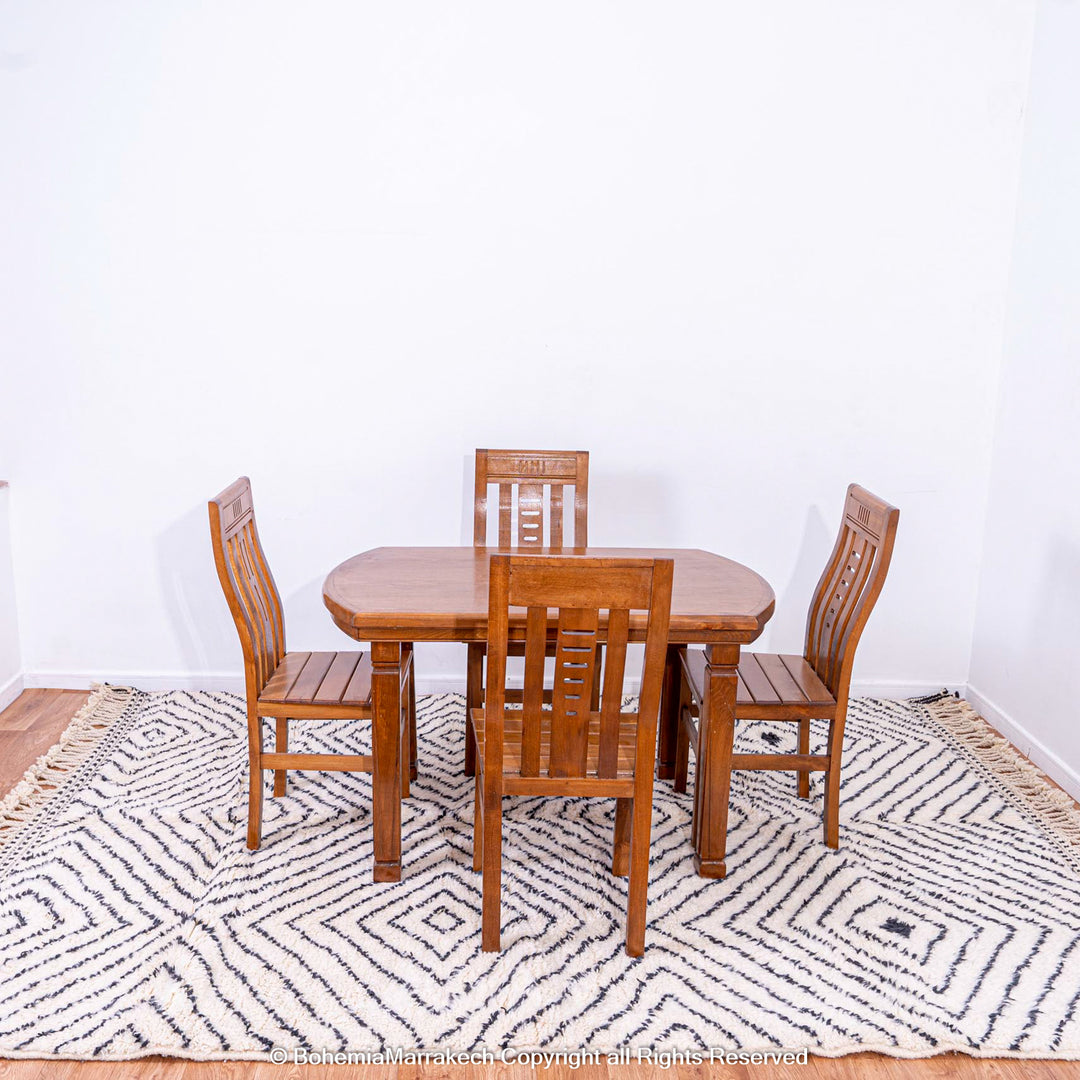 White Moroccan rug with black diamond lines under wooden dining set, handwoven wool, traditional Berber style, area rug for sale.