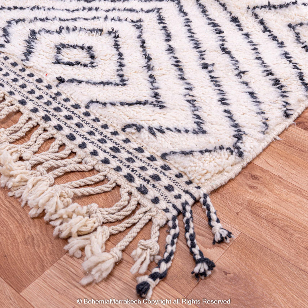 White Moroccan rug with black diamond lines, 100% wool, handwoven by Berber women, showcasing traditional Moroccan design.