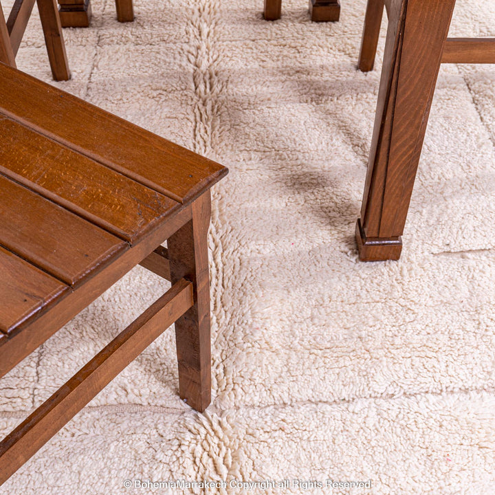 Minimalist off-white Moroccan Berber rug under wooden furniture, showcasing delicate geometric pattern and timeless craftsmanship.